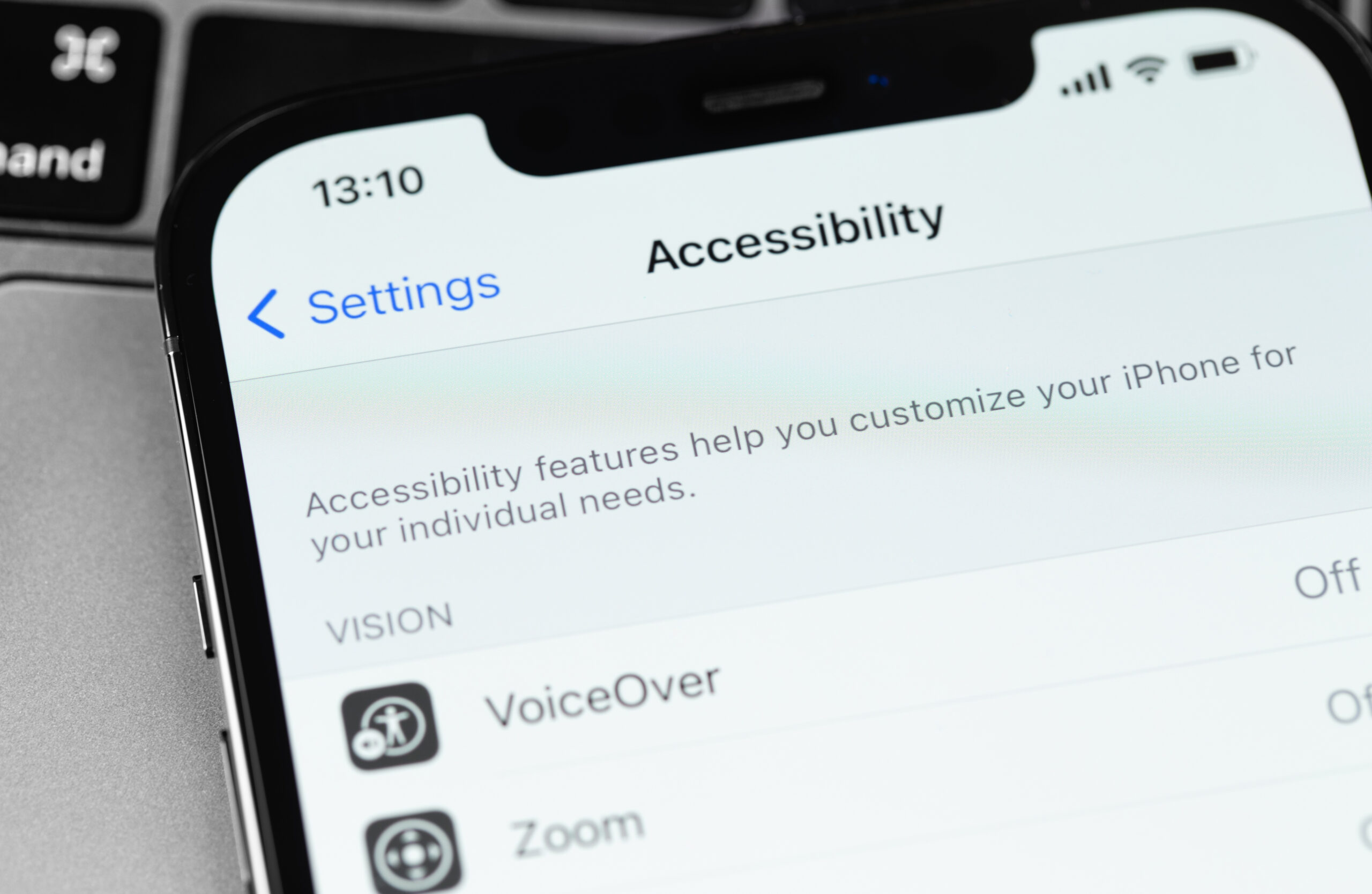 iPhone over the top of MacBook trackpad showing iOS accessibility settings